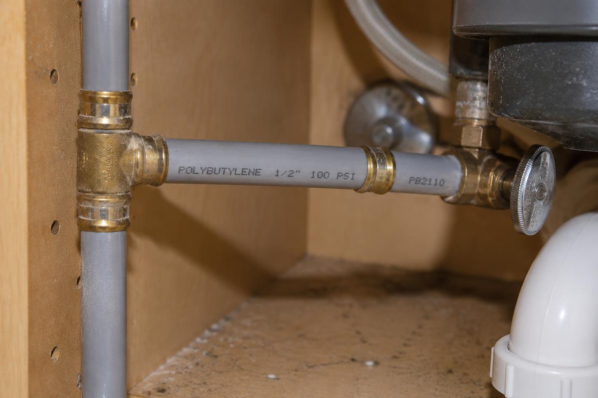 Gray polybutylene pipe under a sink in an older South Florida home.